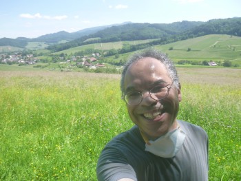 Abie Louis KRIEG on a hill next to some other hills and next to some forests, looking happy